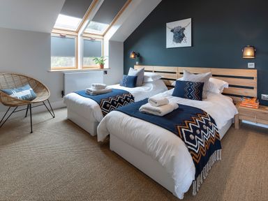 A bedroom with two single beds and a chair under skylight windows at Gatesgarth in Coniston