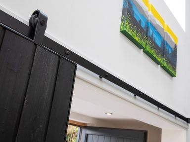 A black sliding barn door on a metal track with a colorful painting above at Gatesgarth in Coniston