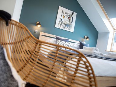 A bedroom with a bed pillows blanket wall lights and an owl painting at Gatesgarth Coniston
