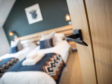 A bedroom with two beds a wooden headboard and a black wall with artwork at Gatesgarth in Coniston