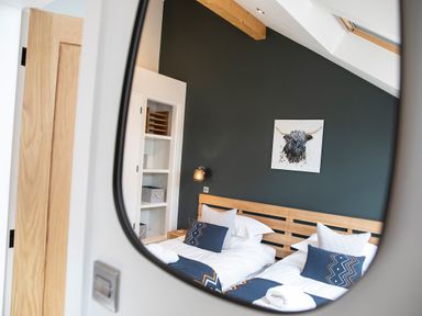 A bedroom with two single beds with patterned cushions and a black accent wall with a painting at Gatesgarth in Coniston