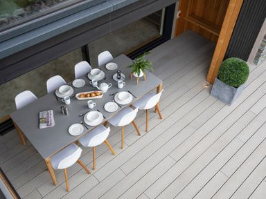 A dining table set with plates cups croissants a teapot and a plant on a patio at Gatesgarth in Coniston