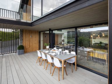 An outdoor dining area with a table set for eight and glass sliding doors at Gatesgarth in Coniston