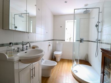 A bathroom with a sink, bidet, toilet, shower, and a small window at Beckhythe Cottage in Overstrand