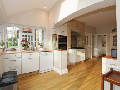 A kitchen with white cabinets a dishwasher a double oven and gas stove at Beckhythe Cottage in Overstrand