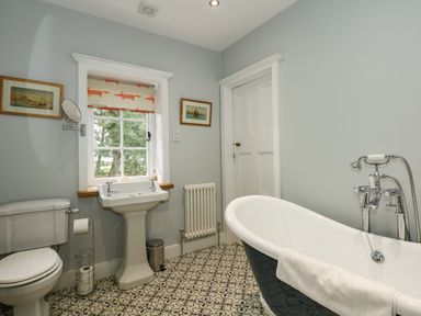 A bathroom with a toilet sink bathtub and patterned floor at Beckhythe Cottage in Overstrand