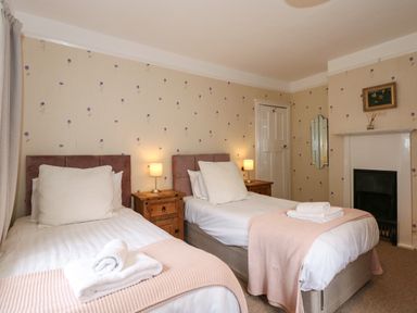 A bedroom with two single beds side by side with nightstands and lamps between at Beckhythe Cottage in Overstrand
