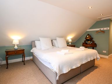 A bedroom with a double bed two bedside tables with lamps and a vanity table at Beckhythe Cottage in Overstrand