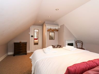 A bedroom with a bed towels on a bed chest of drawers coat rack with hangers and chair at Beckhythe Cottage in Overstrand