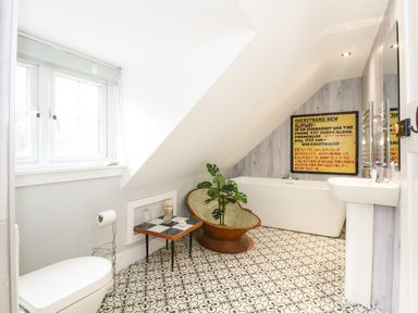 A bathroom with patterned tile floor a bathtub a toilet a pedestal sink a small table and a window at Beckhythe Cottage in Overstrand