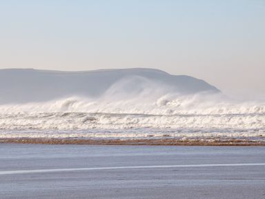 Waves crashing on the shore with hills in the background at Beach Lodge in Woolacombe