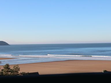 A sandy beach with waves and a clear sky at Beach Lodge in Woolacombe