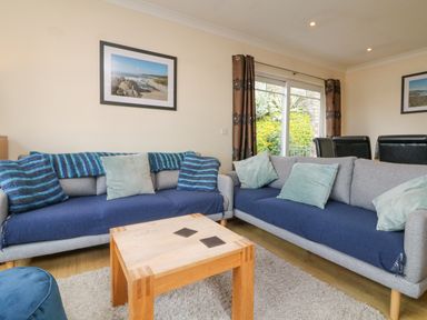 A living room with two sofas a wooden coffee table and framed pictures on the wall at Beach Lodge in Woolacombe