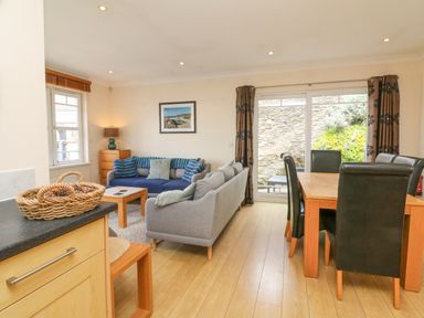 A living and dining area with sofas a wooden dining table with chairs and a sliding glass door at Beach Lodge in Woolacombe