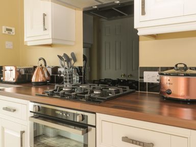 A kitchen countertop with a gas stove oven utensils toaster kettle and slow cooker at Arbour Retreat in Filey