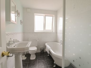 A bathroom with a pedestal sink toilet clawfoot bathtub and frosted glass shower door at Arbour Retreat Filey
