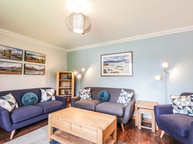 A living room with two purple sofas a purple armchair wooden coffee table and wall art at Silver Birch Lodge in Ratagan Glenshiel near Dornie