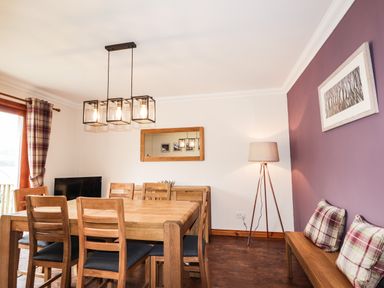 A dining room with wooden table and chairs pendant light floor lamp mirror and framed picture at Silver Birch Lodge in Ratagan Glenshiel near Dornie