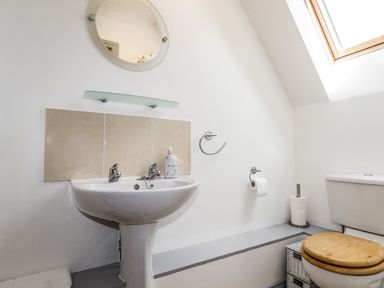 A bathroom with a pedestal sink mirror toilet with wooden seat and skylight window at Silver Birch Lodge Ratagan Glenshiel near Dornie