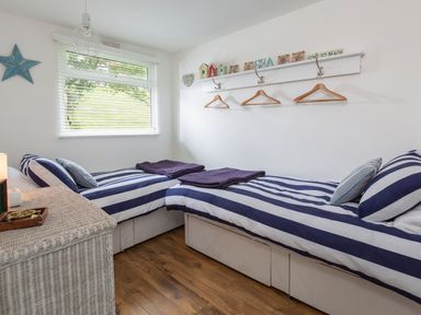 A bedroom with two single beds with striped bedding and wooden hangers on the wall at The Hut in Dartmouth