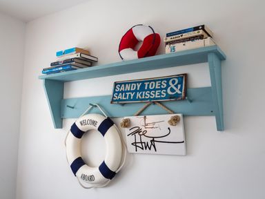 A blue wooden shelf with books and life preservers and nautical signs on a white wall at The Hut in Dartmouth