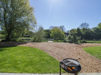 A garden with a barbecue grill and a view of water at Acorn Lodge At Bridge Lake Farm & Fishery Chacombe