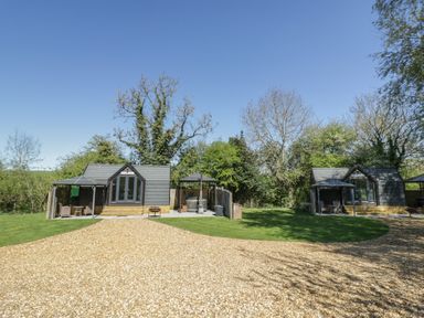Two huts and a gravel driveway in a garden at Acorn Lodge At Bridge Lake Farm & Fishery Chacombe