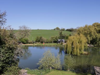 A view of a lake surrounded by greenery at Acorn Lodge At Bridge Lake Farm & Fishery Chacombe