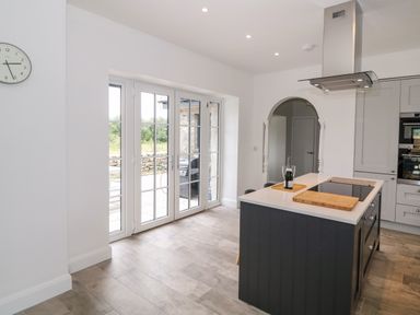 A kitchen with an island countertop and a range hood with doors leading outside at Pen Y Cefn in Pen Y Cefn