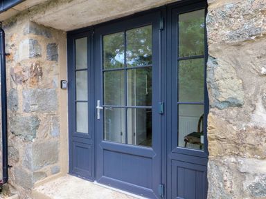 An entrance with double doors and a stone wall at Pen Y Cefn