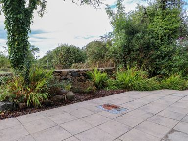 A garden with a stone wall and plants at Pen Y Cefn