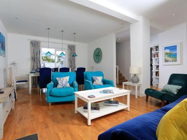 A living room and dining area with blue armchairs a white coffee table and a dining table with blue chairs at Armorel House in Dartmouth