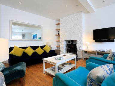 A living room with blue and black seating a white coffee table a stone fireplace and a wall mounted television at Armorel House in Dartmouth