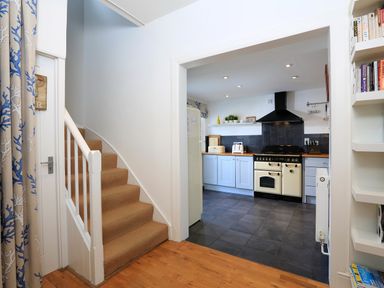 A kitchen with light blue cabinets stove and tiled floor next to carpeted stairs and bookshelf at Armorel House Dartmouth