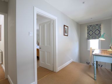 A hallway with a desk and lamp next to a window and an open door leading to a bedroom at Armorel House in Dartmouth