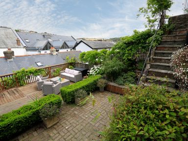 A garden patio with outdoor furniture and stairs surrounded by greenery at Armorel House in Dartmouth