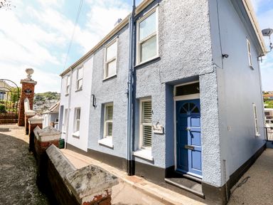 Exterior view of a two-story blue and white terraced house with a blue door at Armorel House in Dartmouth