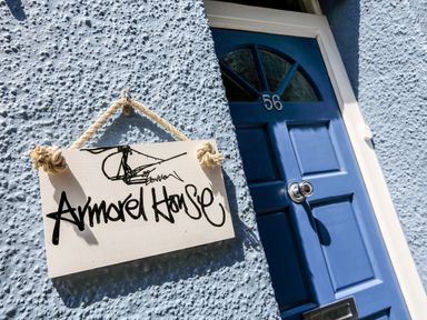 A blue front door with number 56 and a hanging sign saying Armorel House on a textured wall at Armorel House in Dartmouth