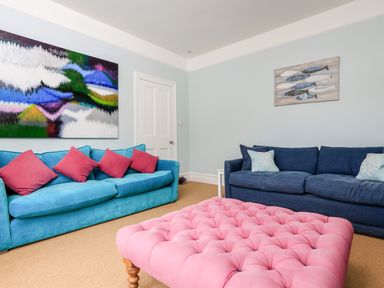 A living room with two sofas and a pink ottoman at Armorel House in Dartmouth
