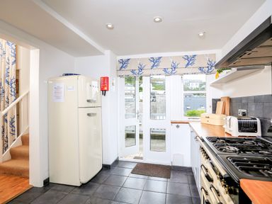 A kitchen with a cream refrigerator stove toaster bread box wooden countertops and glass doors leading outside at Armorel House in Dartmouth