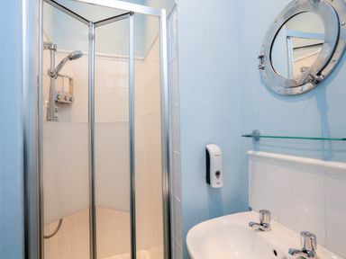 A bathroom with a shower enclosure and a sink with a mirror above at Armorel House in Dartmouth