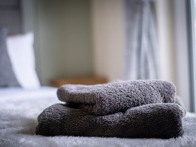 Two folded gray towels on a bed in a bedroom at Otter Lodge in Gargrave