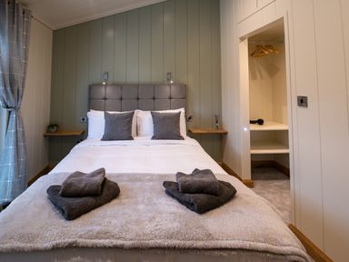 A bedroom with a bed with pillows and folded towels on a fluffy blanket at Otter Lodge in Gargrave