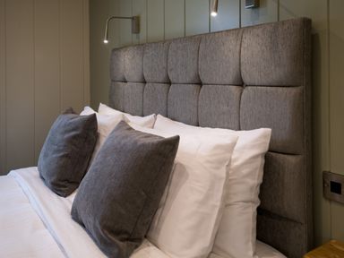 A bed with gray headboard two gray pillows and white pillows at Otter Lodge in Gargrave