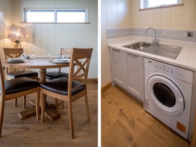 A dining table with chairs and table settings and a kitchen area with a sink and washing machine at Otter Lodge in Gargrave