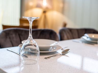 A dining table set with an upside down wine glass plates and cutlery at Otter Lodge in Gargrave