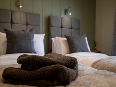 A bedroom with two beds with gray pillows and folded towels at Otter Lodge in Gargrave