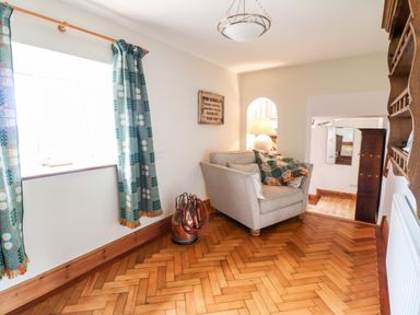 A sitting area with an armchair and patterned curtains at The Stables At Cae Gwyn in Ruthin