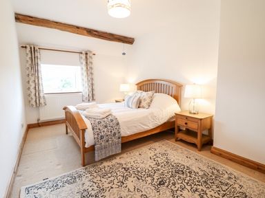 A bedroom with a wooden bed and nightstands with lamps at The Stables At Cae Gwyn in Ruthin