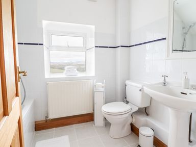 A bathroom with a toilet sink bathtub and window at The Stables At Cae Gwyn in Ruthin